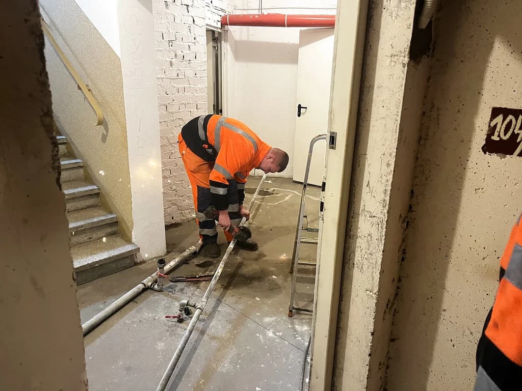 Monter sprawdza przebieg instalacji w piwnicy kamienicy