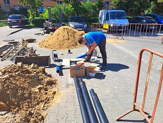 Prace przy rurach odwodnienia na rozkopanym parkingu osiedlowym